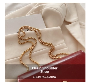Detail of red leather crossbody bag featuring a shiny gold metal ring chain strap