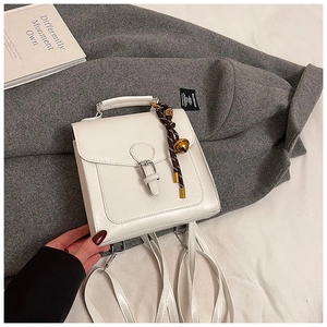 Dettaglio di zaino vintage in pelle bianca con fibbia argentata su fondo in lana grigia