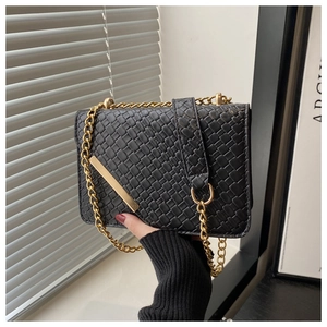 Close-up of black woven shoulder bag with gold chain strap and metallic detail