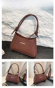 Detail of vintage brown shoulder bag showing golden metal bar and knotted strap design