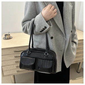 Detailed texture of black crocodile embossed leather on retro Boston bag with two front pockets