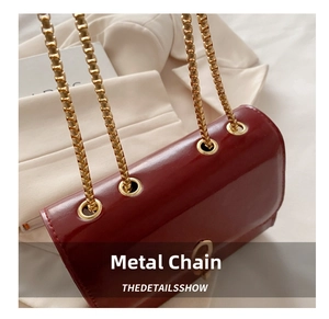 Close-up of golden chain link attachment on burgundy leather square shoulder bag