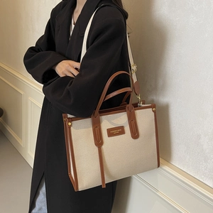 Sac fourre-tout chic en toile avec bordure en cuir marron porté sur le côté