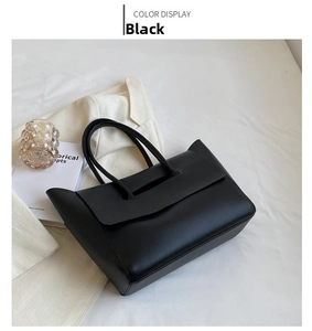 Detail of minimalist black tote bag with wide handles and smooth matte leather texture