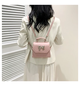 Detail of pink bow mini bag with metallic buckle shown on model in ivory blazer