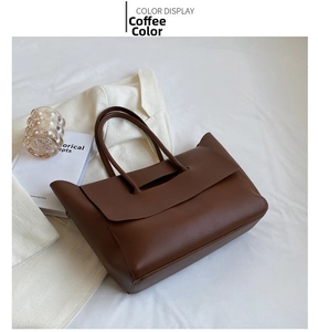 Detail view of coffee-colored faux leather tote bag with elegant handles on white fabric