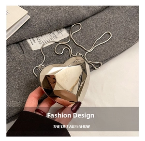 Vue détaillée d'un sac de soirée argenté en forme de cœur avec texture métal facettée