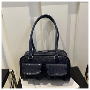 Detail of navy blue crocodile pattern bag featuring double front flap pockets and fine stitching