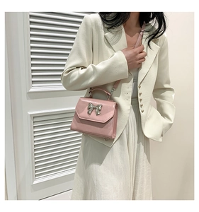 Pink bow handbag shown on model with shiny finish and silver bow detail for elegant style