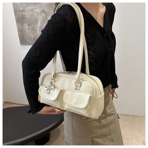 Detail of off-white shoulder bag featuring double pockets and silver bow charm