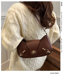Detail of vintage brown leather underarm bag with gold twist lock on knit sweater