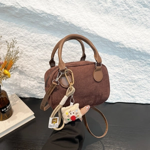 Retro dark brown suede bowling bag with leather handles and a plush charm on side
