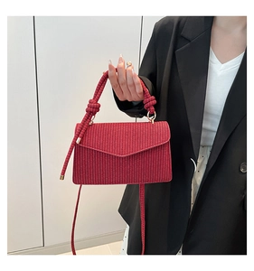Detail of red woven texture handbag with knotted handle and golden metal caps