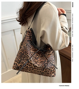 Dettaglio della borsa tote leopardata con fiocco in pelle nera sulla spalla della modella
