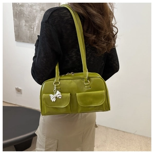 Dettaglio della borsa bowling verde con cuciture bianche e ciondolo a fiocco argento