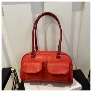 Detail of red faux leather tote bag featuring crocodile pattern and dual front flap pockets