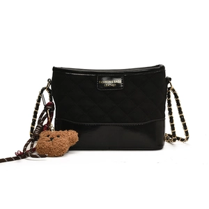 Black quilted crossbody bag with gold chain strap and brown teddy bear pendant