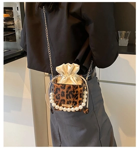 Detalle de bolso saco de leopardo con asa de perlas y correa de cadena dorada