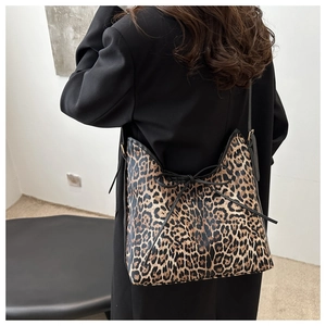 Detail of leopard print tote bag featuring a black bow tie and premium leather piping