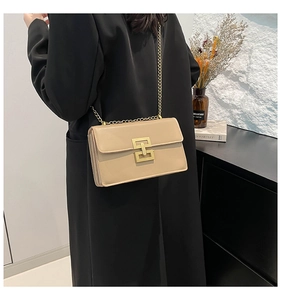 Détail d'un sac bandoulière beige avec fermoir doré emboîtable et bandoulière chaîne