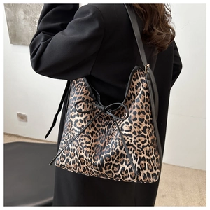 Détail du sac cabas léopard avec un nœud décoratif noir et une bandoulière chic