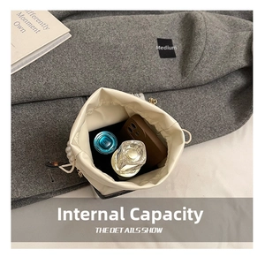 Interior view of off-white drawstring bucket bag showing storage capacity for phone and perfume