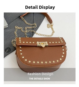 Macro shot of brown lychee grain leather saddle bag with gold rivets and chain strap detail