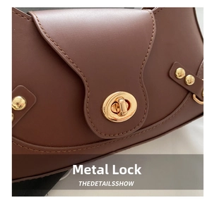 Detailed close-up of a vintage brown leather handbag featuring a golden turn-lock closure