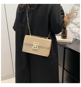 Détail d'un sac bandoulière en cuir beige avec chaîne dorée et boucle métal