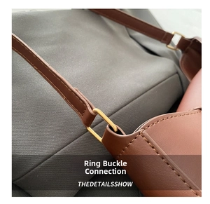 Detailed close-up of the golden D-ring hardware and stitching on a brown leather bag