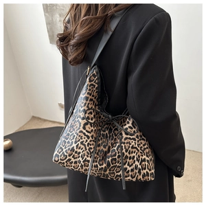 Detailed side view of leopard print tote bag with black bow and wide shoulder strap