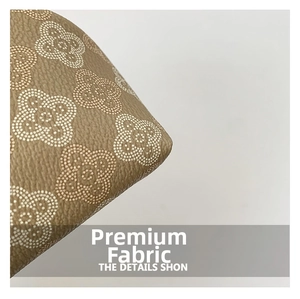 Macro detail of khaki litchi grain leather shell bag with white floral pattern