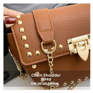Close-up of brown pebbled leather texture with gold pyramid studs and metallic chain strap