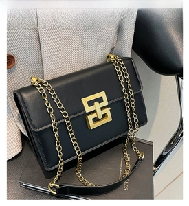 Détail du sac bandoulière en cuir noir avec fermoir géométrique doré et bandoulière chaîne