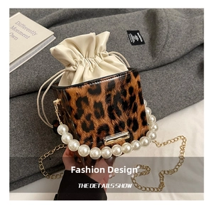 Close-up of leopard print square bag with pearl handle, gold chain and drawstring liner