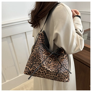 Close-up of leopard print tote bag with black ribbon bow shown on a model's shoulder