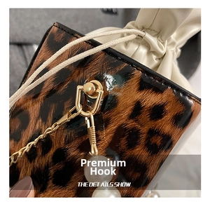 Close-up of golden hardware, pearl charms and glossy leopard print on a crossbody bag