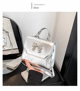 Detail of silver metallic handbag featuring bow decoration and wrinkled texture finish
