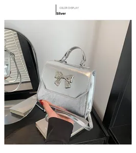Detail of silver metallic handbag featuring bow decoration and wrinkled texture finish