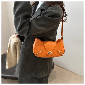 Close-up of vibrant orange leather baguette bag with silver rivets and metal clasp