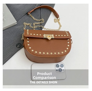 Detail view of brown saddle bag with golden rivets and chain strap next to a smartphone