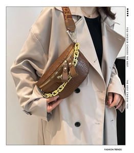 Detail einer braunen Brusttasche mit Krokodilmuster, Goldkette und breitem Trageriemen