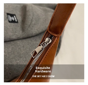 Close-up of high-quality silver metal zipper on a textured brown leather shoulder bag