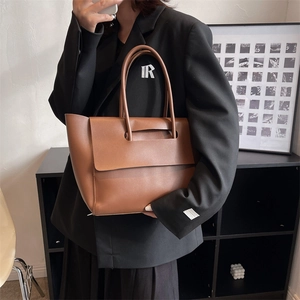 Minimalist brown vintage leather tote bag shown with an elegant model in black suit