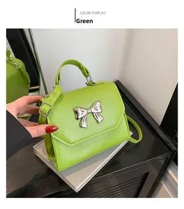 Close-up of bright green small square handbag with shiny silver metal bow decoration