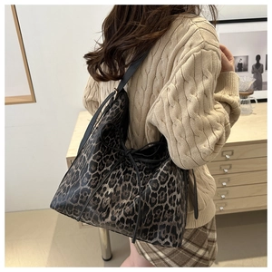 Detail of leopard print tote bag featuring black leather drawstring and shoulder strap