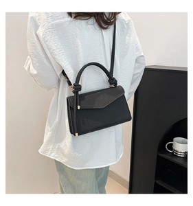 Detail of a black woven shoulder bag featuring a knotted handle and gold-tone hardware
