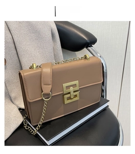 Détail d'un sac bandoulière en cuir marron avec fermoir doré et bandoulière chaîne