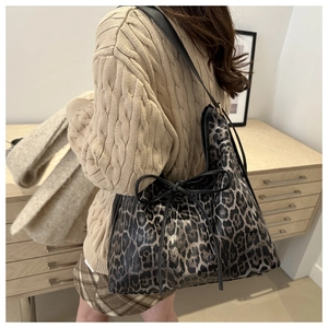 Vista laterale della borsa tote leopardata con fiocchi neri su una modella