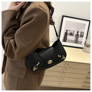 Detail of vintage black leather underarm bag with gold lock and metallic rivet accents